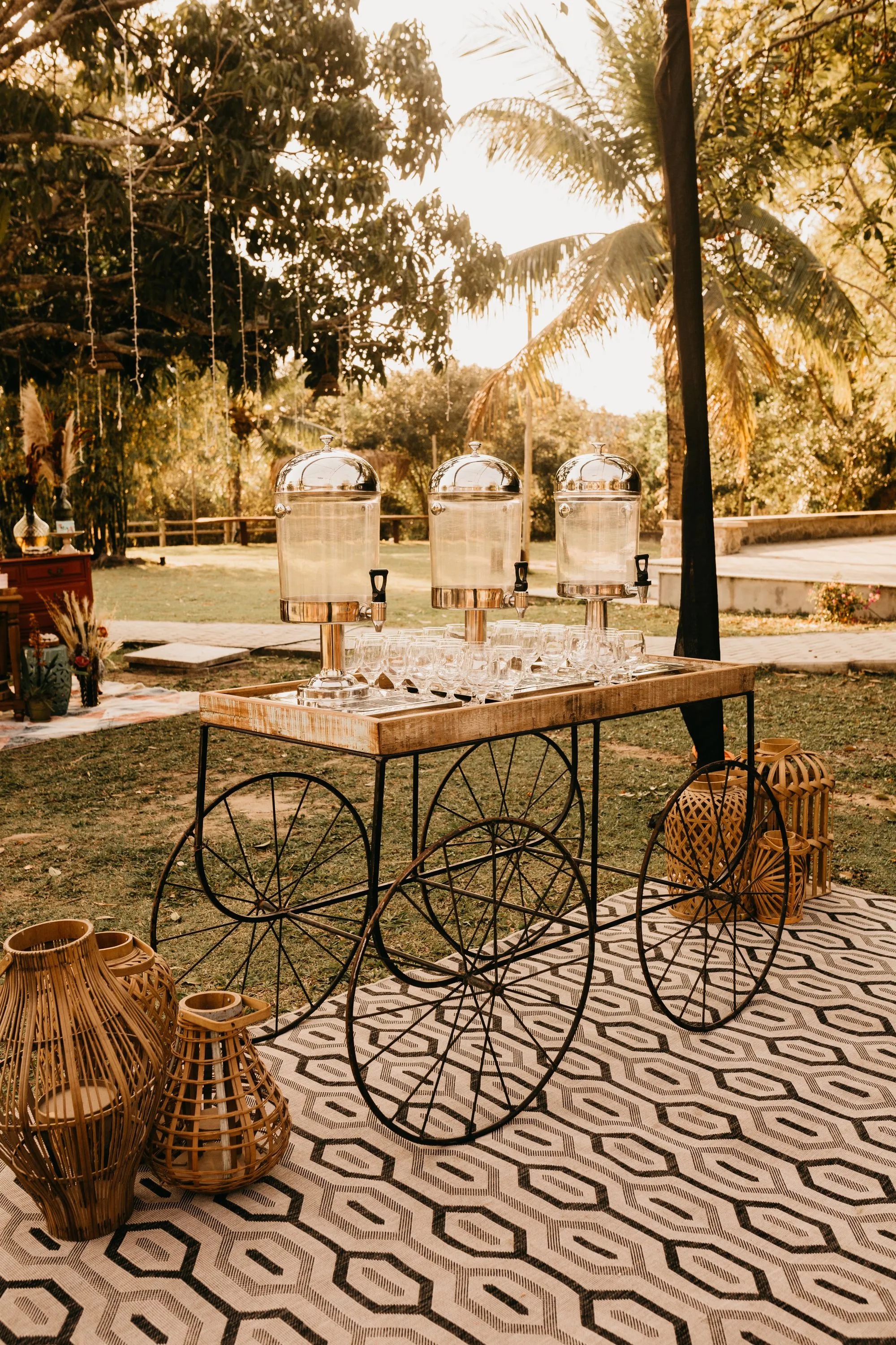 An outdoor reception service table dressed with candelabras, glassware and greenery