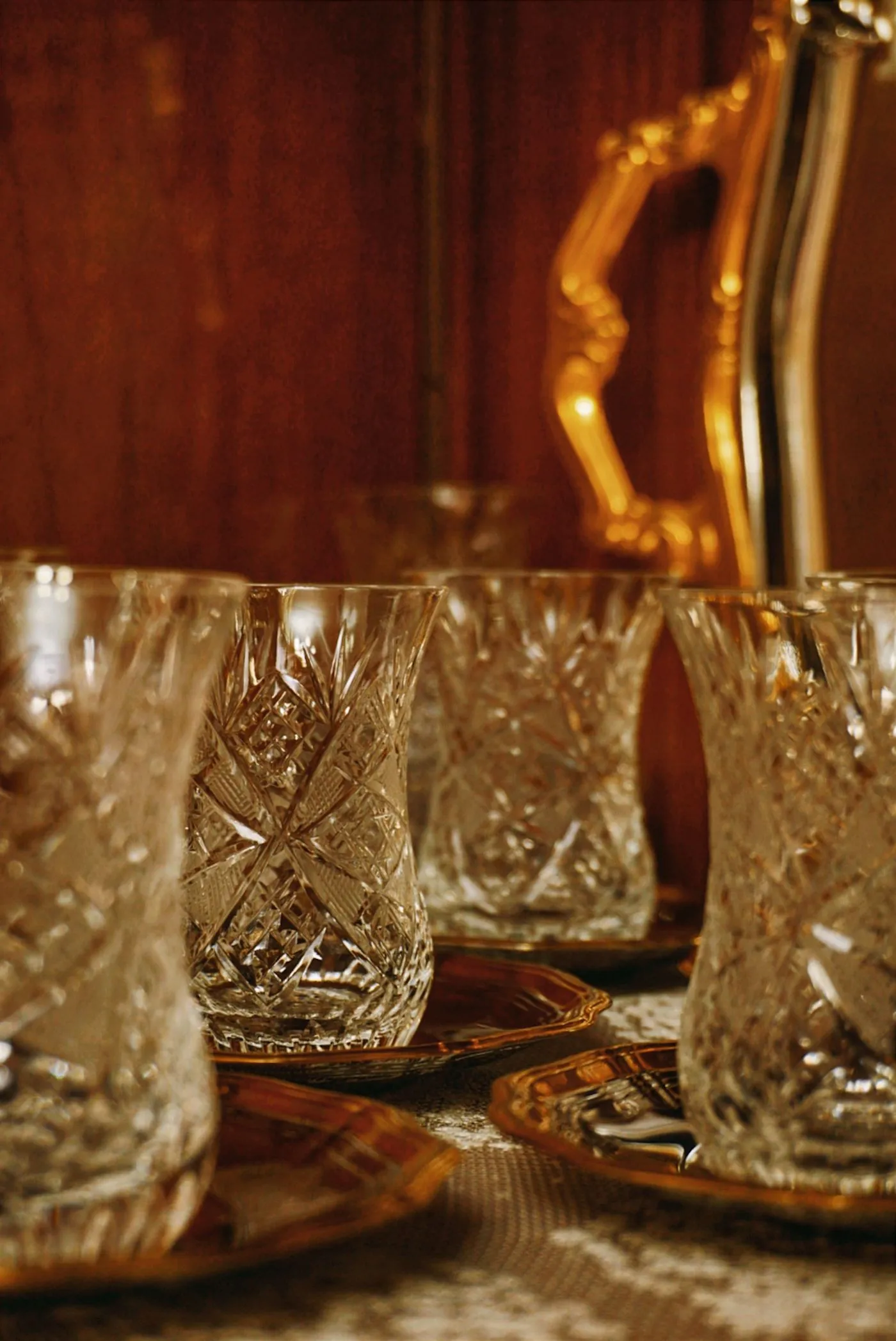 Cut-crystal glasses arranged on a gilt serving tray in warm light