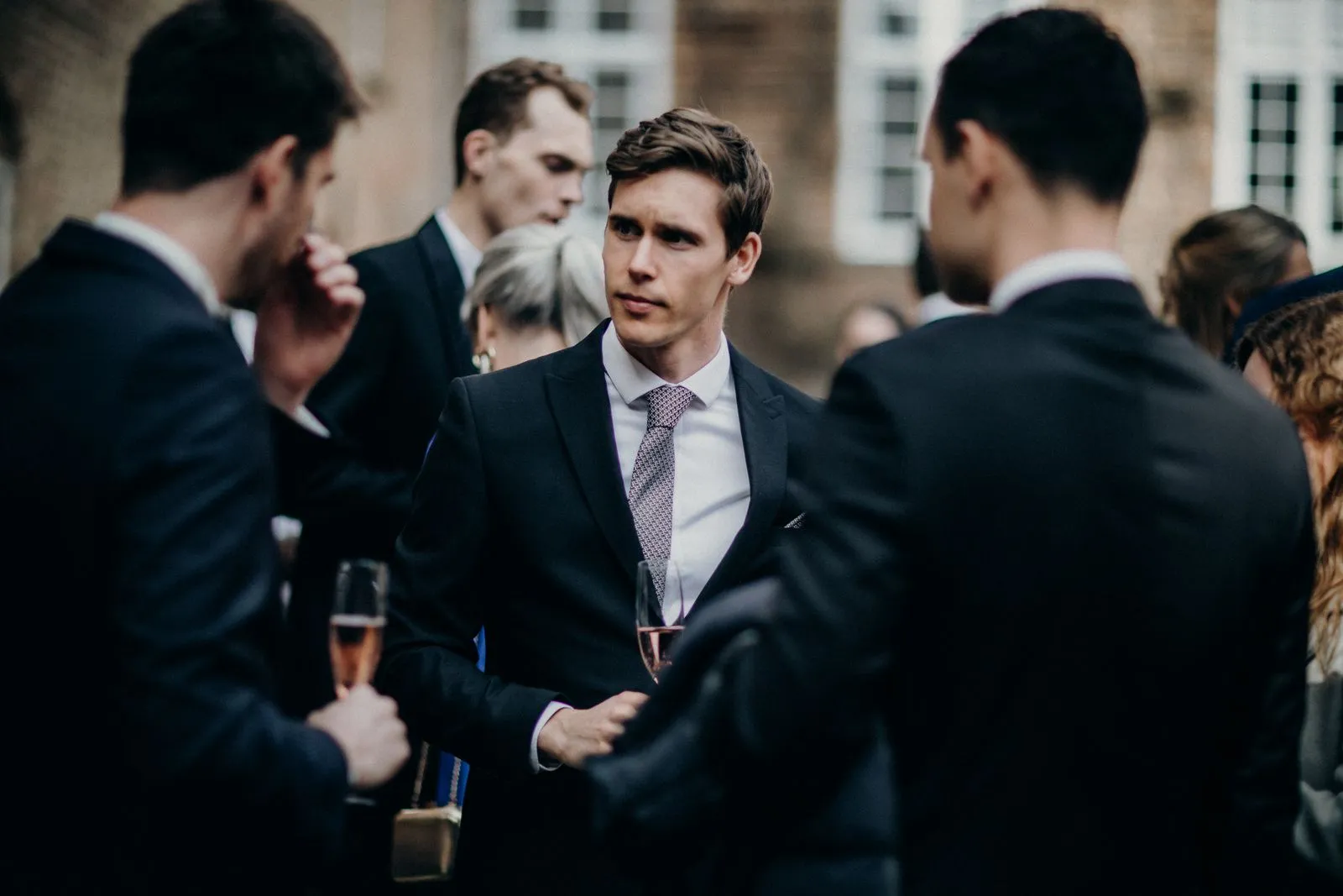 Guests in suits talking over drinks at an outdoor corporate function
