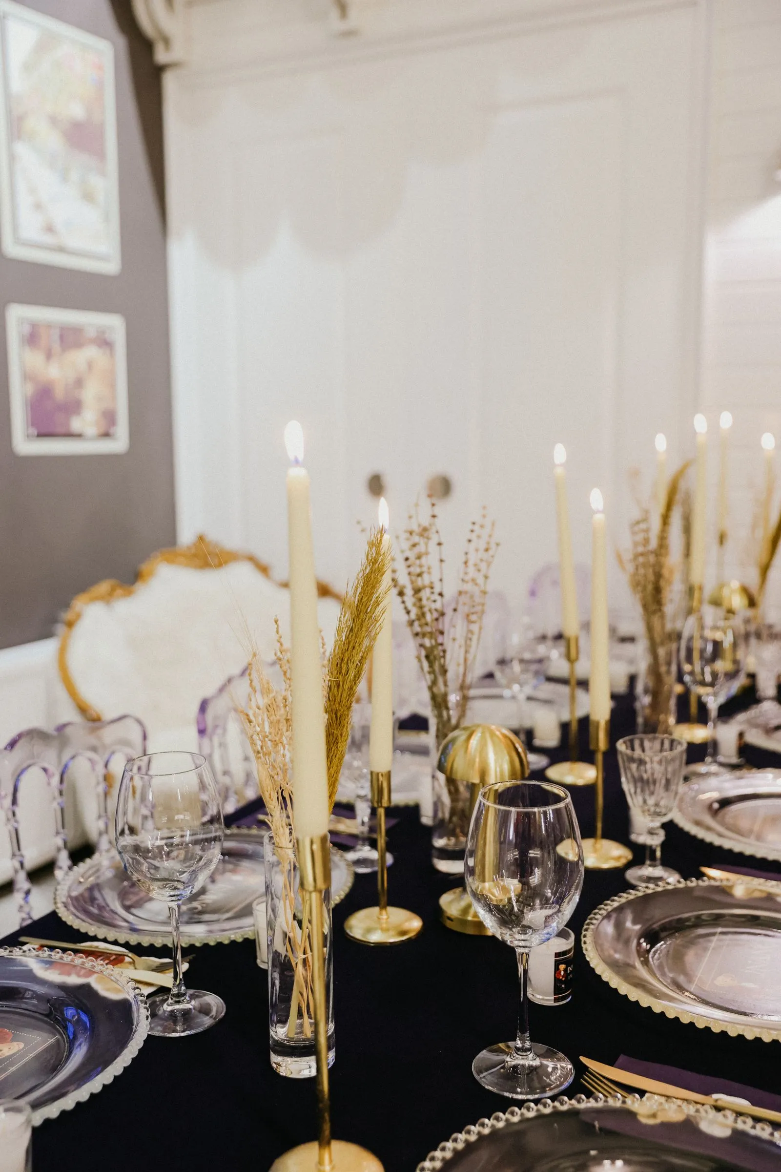 A long dinner table set with tapered candles, fine china and gilt chairs