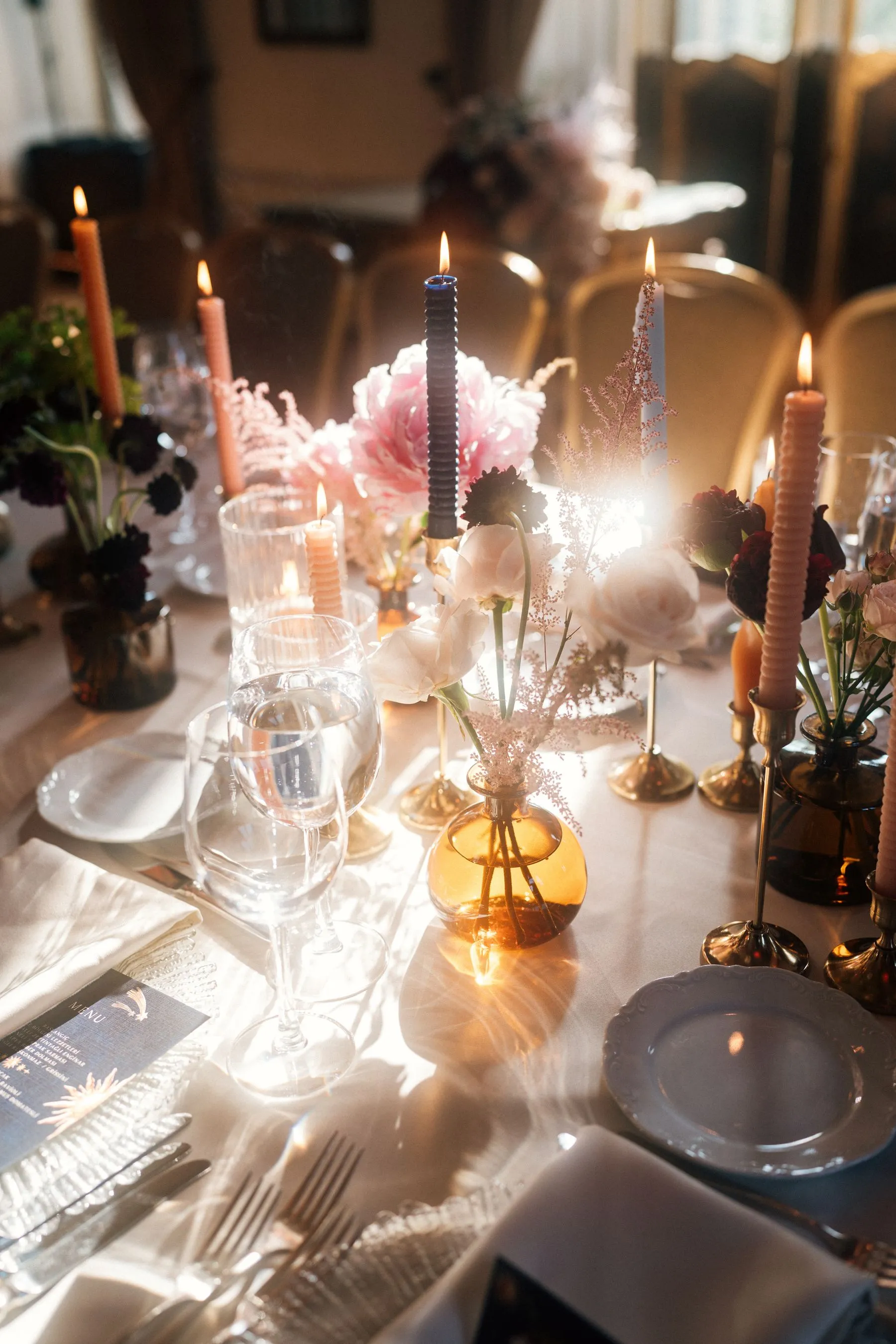 A candlelit dinner table dressed with white florals, crystal glassware and gold detailing