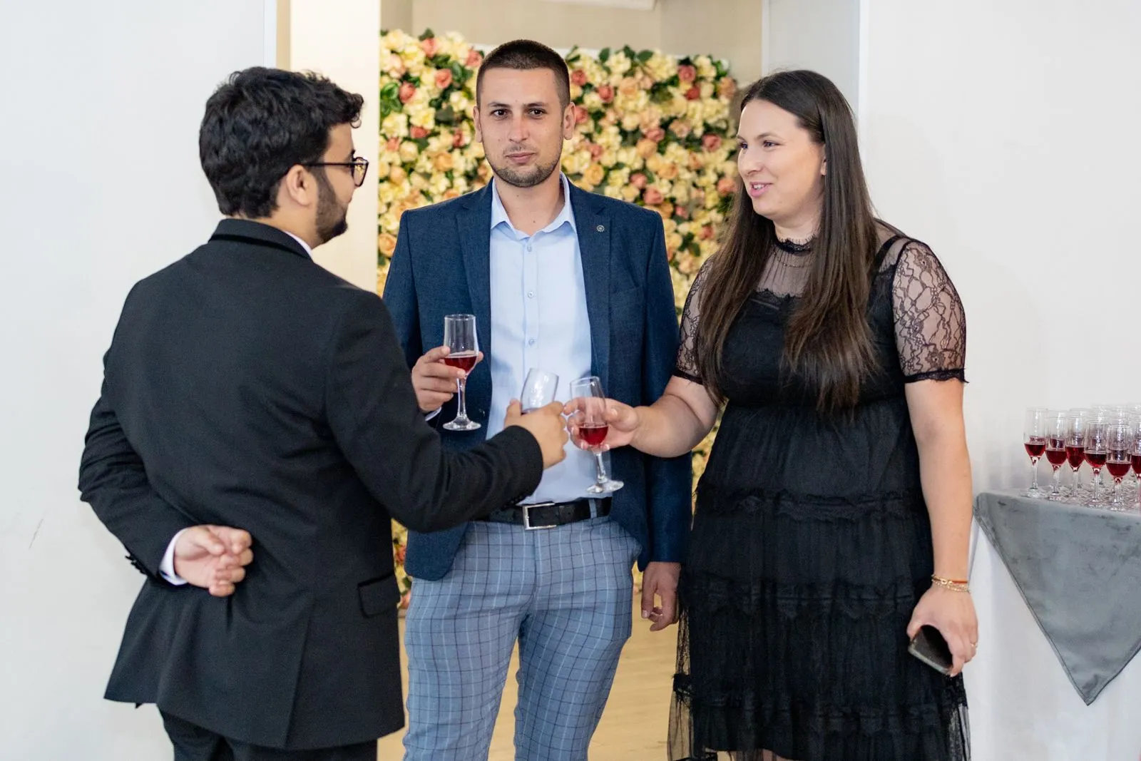 Three guests raising glasses together at an evening celebration