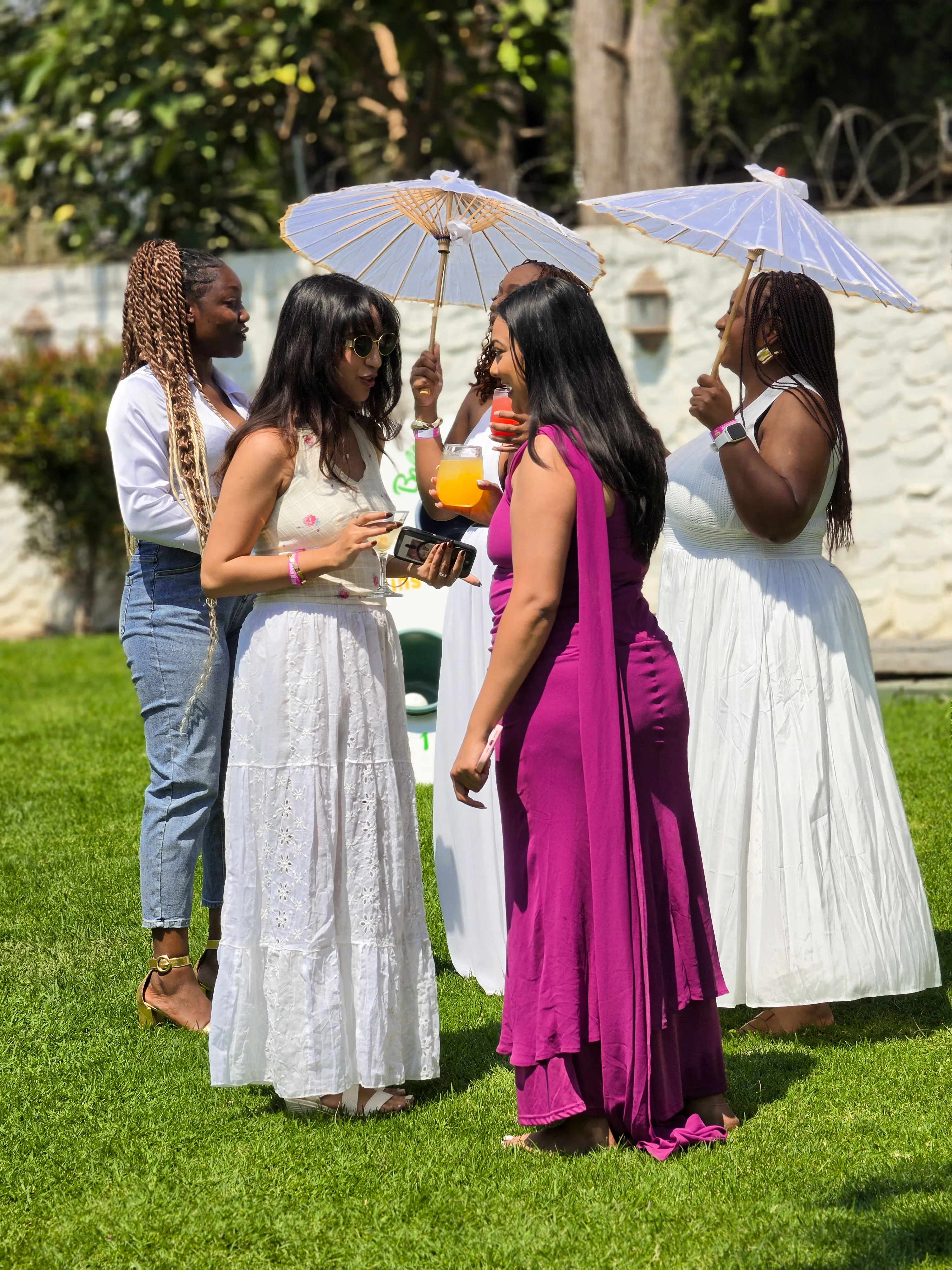 Guests chatting with colourful drinks and white parasols on the lawn at the KaizenCo launch
